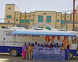 Group of people holding a banner in front of a mobile health center.