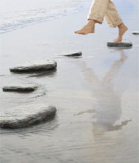Photograph of feet using stepping stones to navigate the beach.