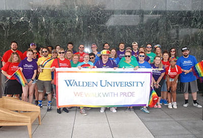 Walden staff hold a banner that reads 'We walk with pride.'