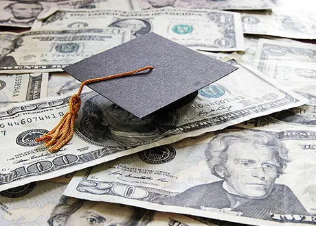 Graduation cap over several dollar bills