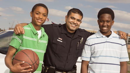 A police officer standing up with two black young men
