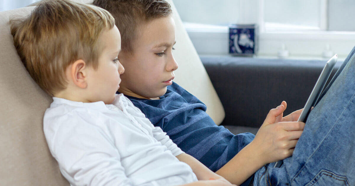 Two young boys looking at tablet device.