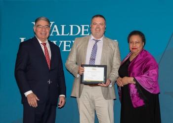 Dr. Eric Sarrett receives the Harold L. Hodgkinson Award for Outstanding Dissertation from Walden board of directors member Dr. Stan Paz and chair Toni Freeman. 