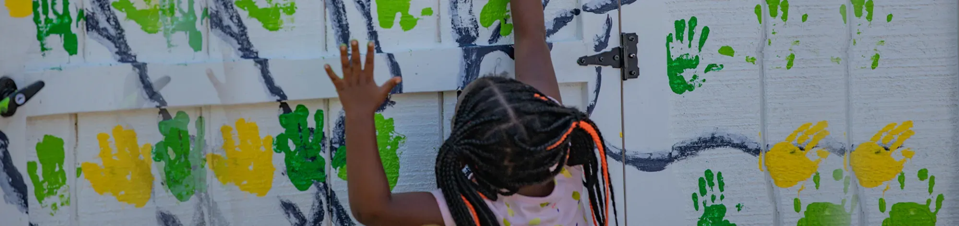 kid paiting a wall using her hand